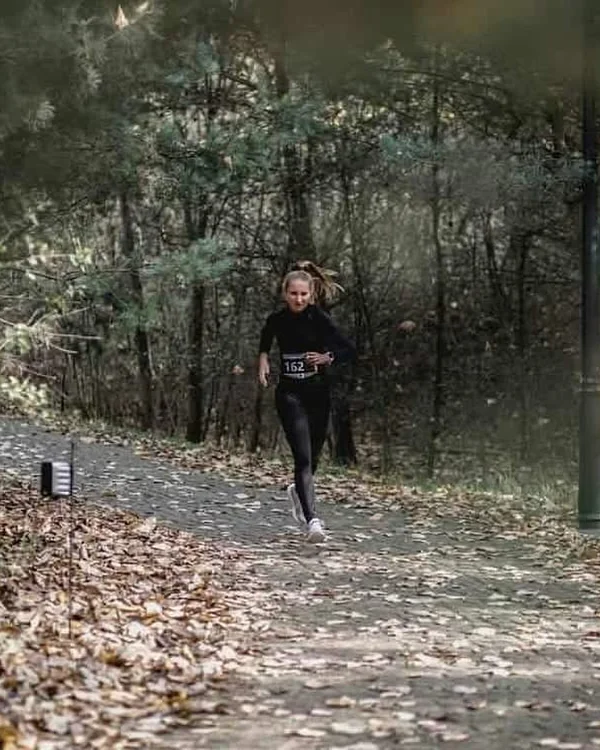 Patrycja podczas biegu w jesiennej scenerii, skupiona na trasie.