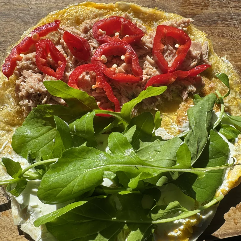 Omlet białkowy z tuńczykiem i rukolą na talerzu.